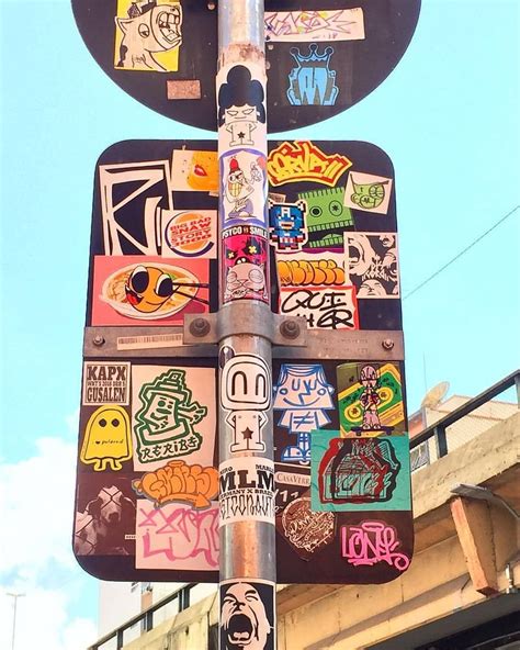 A Street Sign With Many Stickers On It