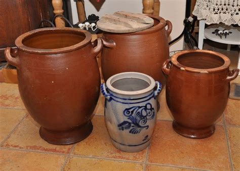 Three Clay Pots Sitting On Top Of A Tile Floor Next To A Wooden Table