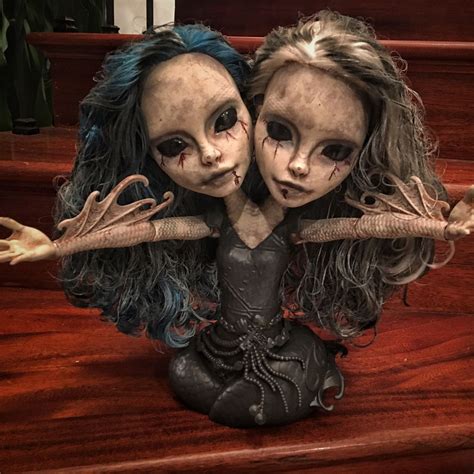 Two Creepy Dolls Sitting On Top Of A Wooden Table