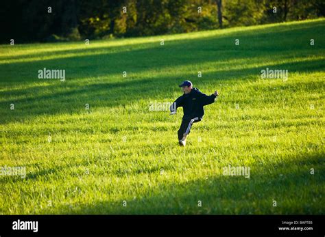 Teenage Boy Running In The Green Grassy Fields Of A Park Stock Photo