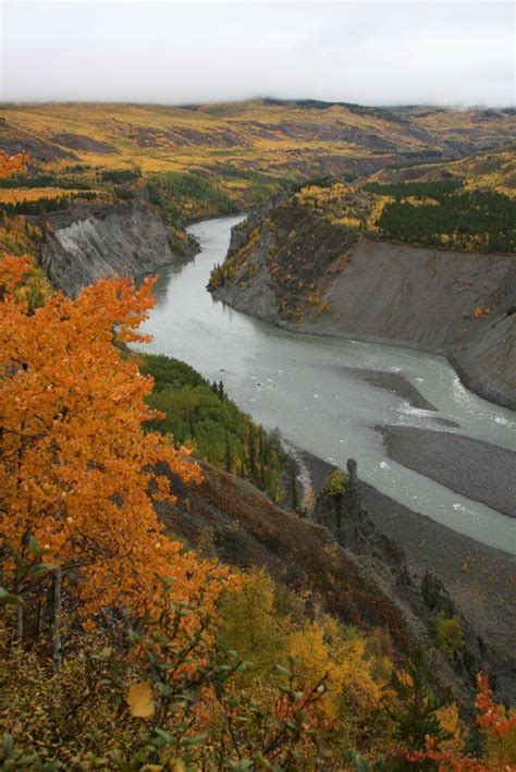 A River Flowing Through A Valley Surrounded By Mountains And Trees In