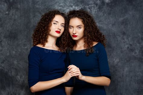 Sisters Twins Smiling Winking Looking At Camera Over Grey Background