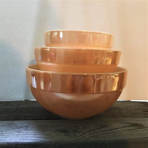 Three Bowls Stacked On Top Of Each Other In Front Of A Wall And Wood Floor