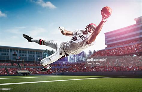 American Football Player Catching Ball Mid Air In Stadium Foto Stock