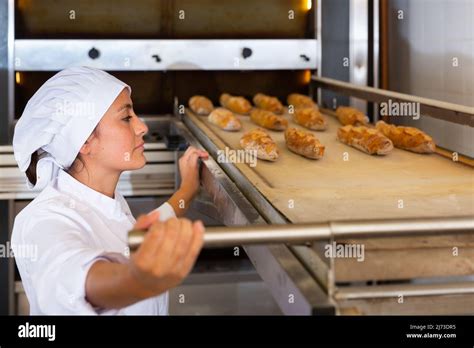 Female Bakery Worker Pulls Bread Pan Out Of Oven Stock Photo Alamy