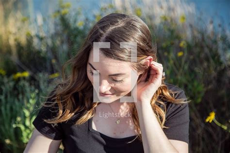 a woman tucking her hair behind her ear — photo — lightstock