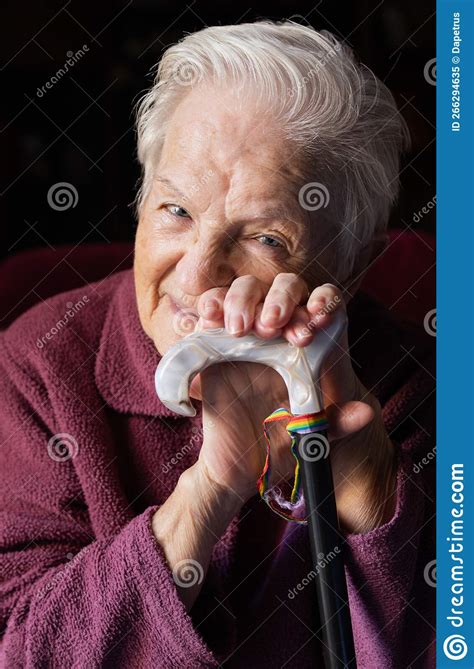 Elderly Woman With A Happy Smile With Gay Rainbow Ribbon On Her Cane