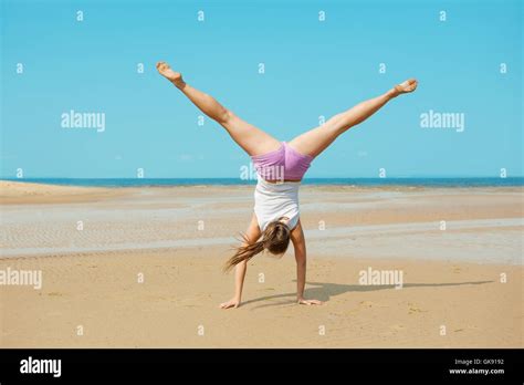 Beautiful Energetic Young Woman Doing Handstand On The Beach Stock