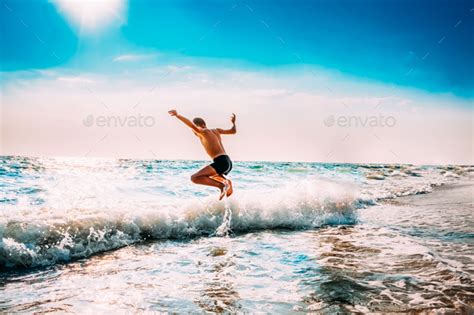 Boy Having Fun And Jumping In Sea Ocean Waves Jump Accompanied Stock