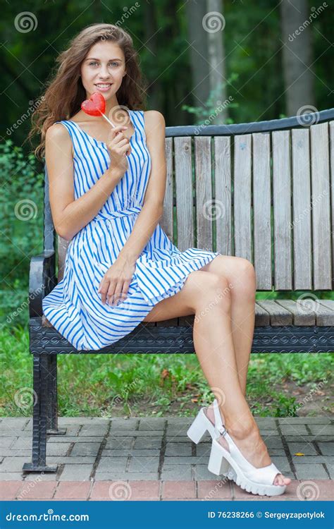 Spring Beautiful Woman In Summer Dress Sitting On The Bench In Green