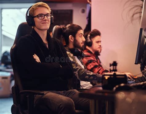 A Smiling Gamer Wearing A Sweater And Glasses With His Arms Crossed
