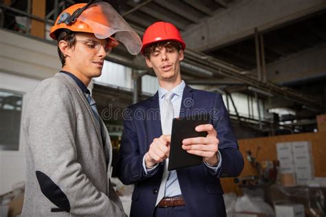 Two Engineers Discuss A Project Using A Tablet While They Are In The