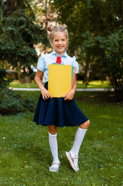 Premium Photo Happy Schoolgirl Holding A Book Outdoors A Small Child