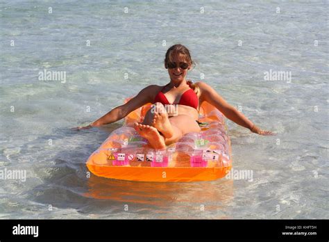 A Tanned White Girl In Bikini Trying To Move With Her Inflatable Rubber Raft Stock Photo Alamy