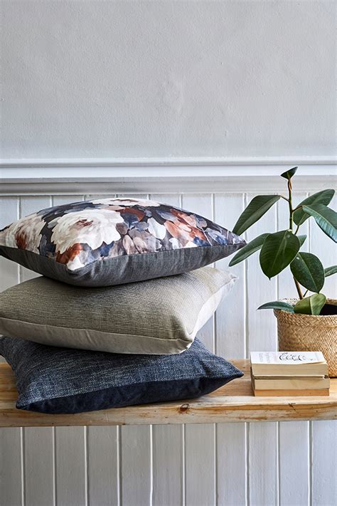 Three Pillows Stacked On Top Of Each Other Next To A Potted Plant