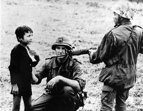 A Us Soldier And A South Vietnamese Soldier Questioning A Child In A