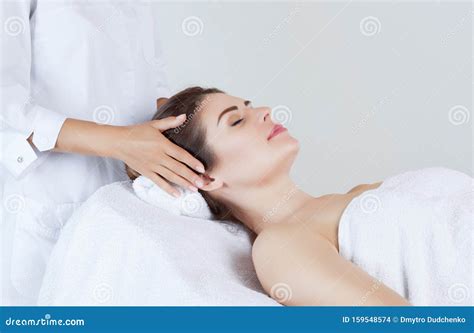 masseur makes a relaxing massage on the face neck and shoulders of a beautiful woman in a spa