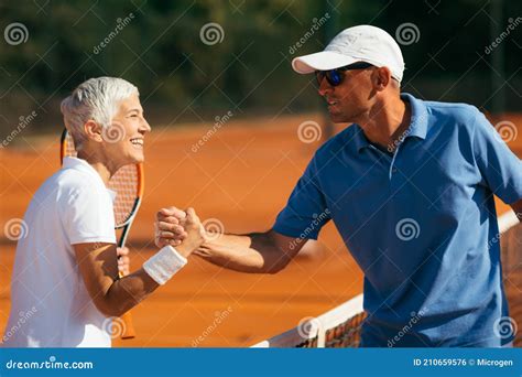 Tennis Instructor With Senior Woman In Her 60s Handshaking After Having A Tennis Lesson On Clay