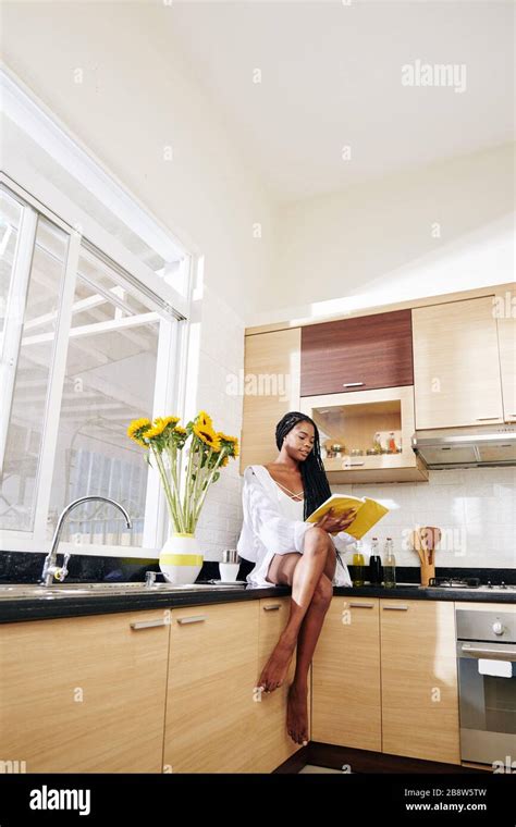 Attractive Young Black Woman In Lounge Wear Sitting On Kitchen Counter