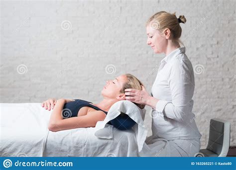 Professional Female Masseur Giving Relaxing Massage Treatment To Young