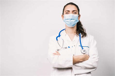 self assured female doctor in uniform with stethoscope and sterile mask looking at camera with