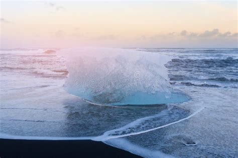 Iceberg From Black Sand Beach With Sea Coast Skyline Stock Photo
