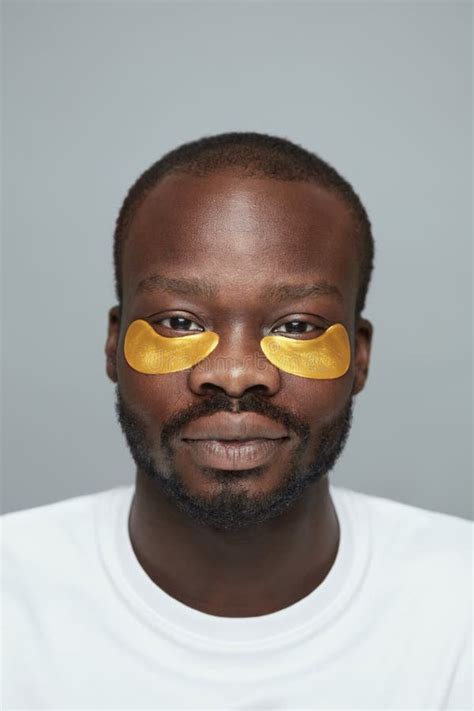 Skin Care Portrait Of Male Model Applying Yellow Under Eye Patches