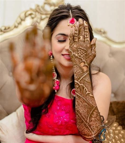 A Woman Holding Her Hands Up To Show The Henna On Her Face And Arm