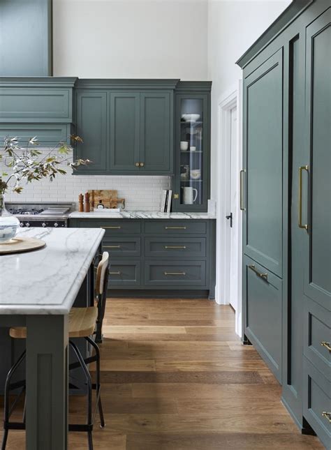 A Large Kitchen With Green Cabinets And White Counter Tops Along With