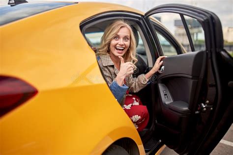 Photo Of Enthusiastic Blonde Sitting In Back Seat Of Yellow Taxi With