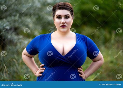 Plus Size Fashion Model In Blue Dress With A Deep Neckline Outdoors