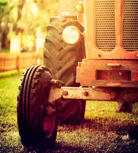 Old Vintage Red Tractor Standing On A Farm Field At Sunset Stock Photo