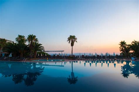 Swimming Pool With Palm Trees At Sunset Water Reflection Stock Photo