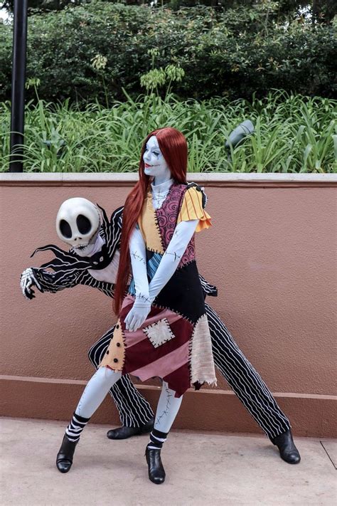 A Woman With Red Hair And Makeup Is Holding A Skeleton In Her Hand While Standing Next To A Wall