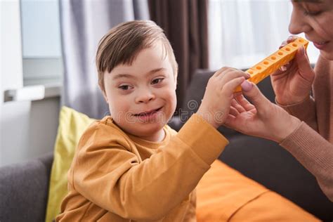 Caucasian Mother Playing At The Building Kit With Her Son With Down Syndrome While Sitting Stock