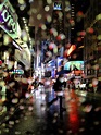 / gotas de lluvia en la lente de la cámara con calles nocturnas urbanas ...
