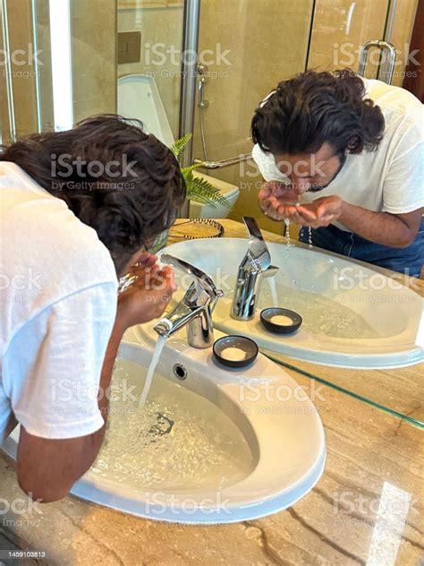 Closeup Image Reflection In Mirror Of Indian Man Bent Over Sink Full Of