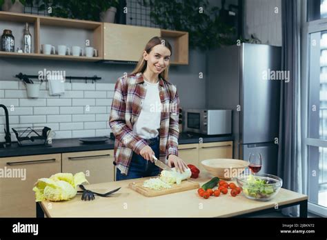 Beautiful Young Blonde Woman Cooking At Home Chopping Vegetables