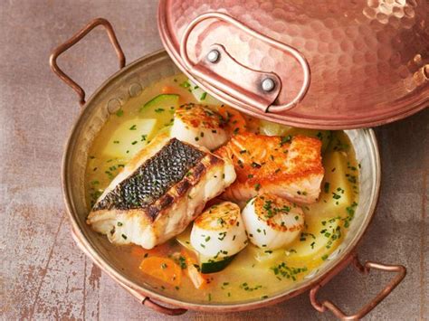 Some Fish And Potatoes In A Bowl With A Copper Pot On The Table Next To It
