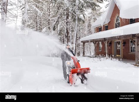 Man With A Snow Blower Clearing A Driveway In A Beautiful Snowy