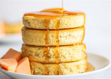 A Stack Of Pancakes On A Plate With Syrup Being Drizzled Over Them