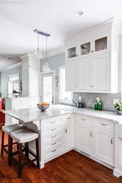 This modern kitchen features a gray and white color scheme, with a marble waterfall edge kitchen island, marble backsplash and stainless steel appliances. Pin by myralsmith on For the Home | Modern white kitchen cabinets, White modern kitchen, Kitchen ...