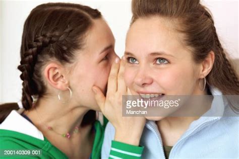 Two Teenage Girls One Whispering Into Anothers Ear Close Up High Res