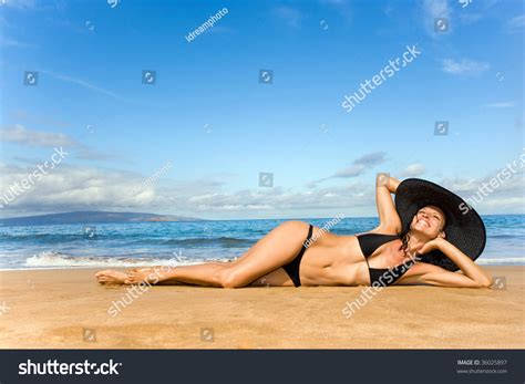 Woman In Elegant Black Bikini And Wide Brim Hat On Tropical Maui Beach In Hawaii Sunbathing And