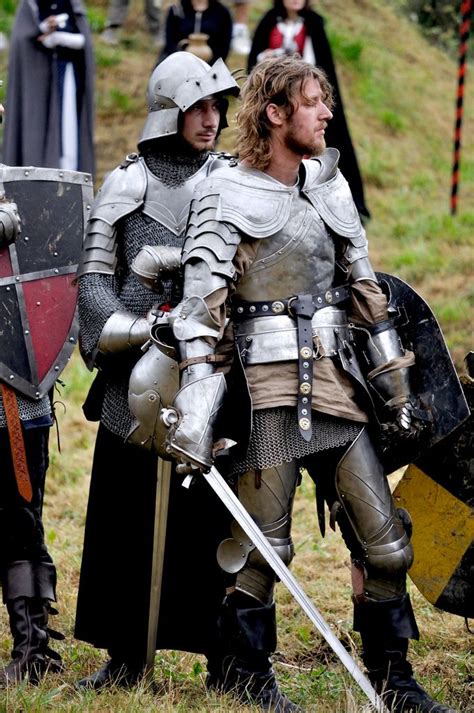 Two Men Dressed In Medieval Armor Standing Next To Each Other On A