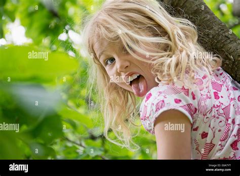Junge Mädchen Sitzt Im Baum Die Zunge Heraus Stockfotografie Alamy