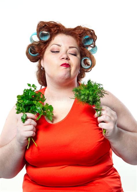 fat woman with sensuality red lipstick in curlers on a diet holding parsley and dill stock image