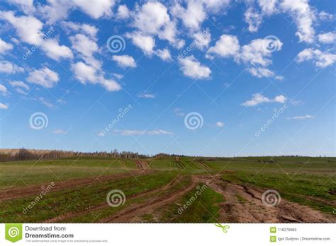 Field Dirt Road Goes Beyond The Horizon And White Clouds In The Blue
