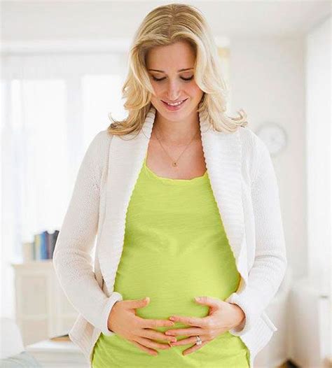 A Pregnant Woman Is Holding Her Stomach In The Living Room