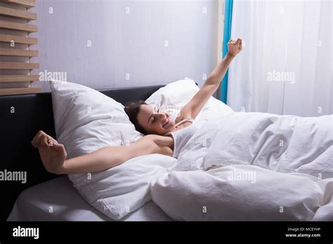 Young Woman Waking Up Stretching Her Hands On Bed Stock Photo Alamy